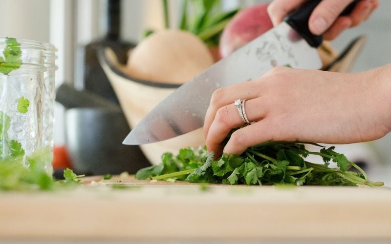 Close up of hand chopping cilantro on kitchen counter