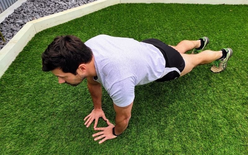 Athletic man doing diamond push up's outside