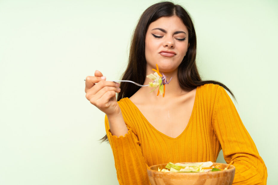 Teenager girl with salad over green wall